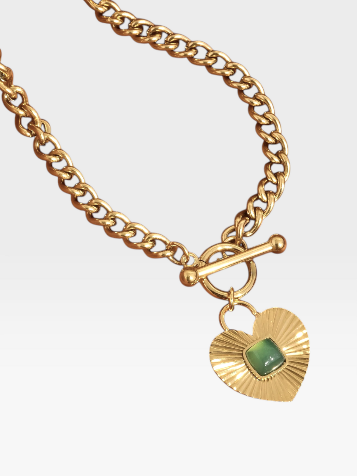 TheConsignmentBar 18K gold non-tarnish chain necklace featuring a textured heart pendant with a green center stone.