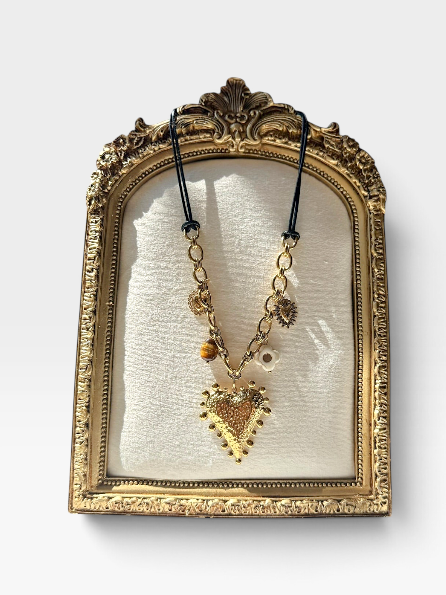 TheConsignmentBar 18K gold heart charm necklace featuring a textured heart pendant, flower, and stone accents on a cord