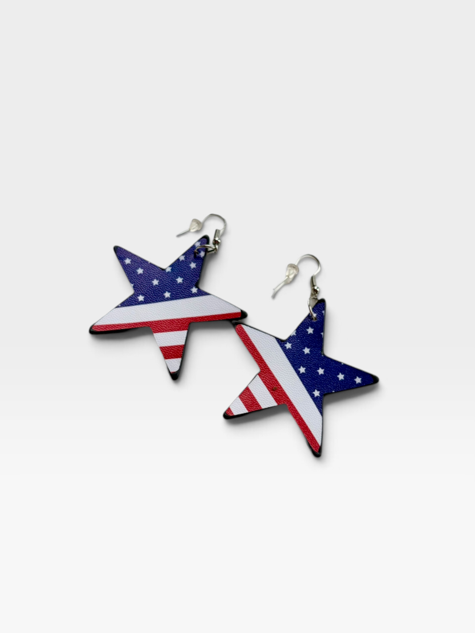 TheConsignmentBar AURORA star-shaped earrings featuring a red, white, and blue American flag pattern on a white tray.