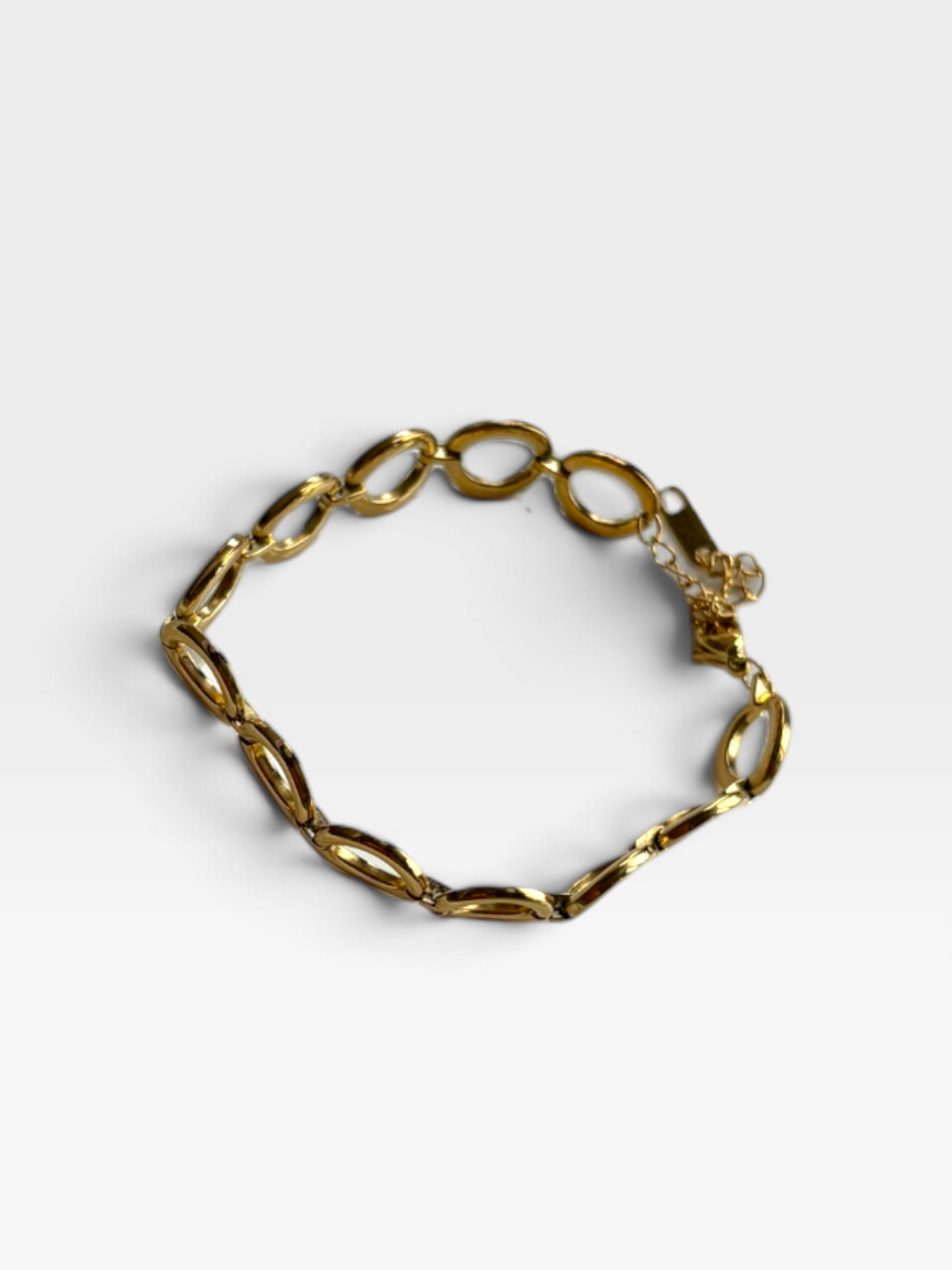 TheConsignmentBar MIO 18K gold plated oval linked bracelet resting on a white wavy ceramic dish