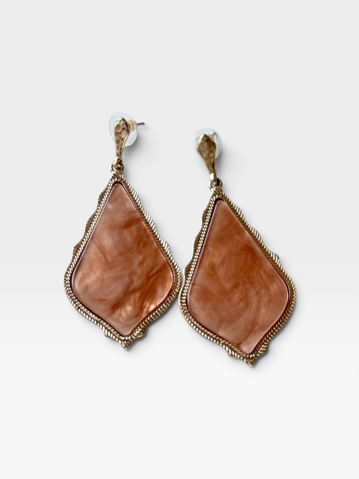 TheConsignmentBar Kendra Scott gold drop earrings featuring a diamond-shaped peach marbled stone and textured frame.